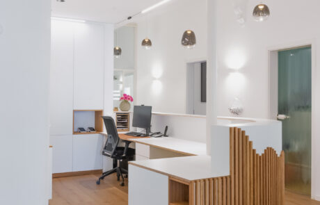 breite moderne Empfangstheke nach Maß in einer Praxis mit Abrundung, Regal, Schrank und Dekorativen Holzelementen von einer Schreinerei Nähe Freiburg gefertigt von der Schreinerei und Möbelwerkstatt HÄRING in March